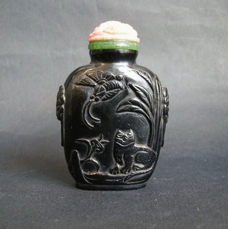 Snuff Bottles : snuff bottle "jais"   sculpted in low relief  with a cat looking a butterfly  and other face with two rabbits . Mask on the sides - 19th century - 