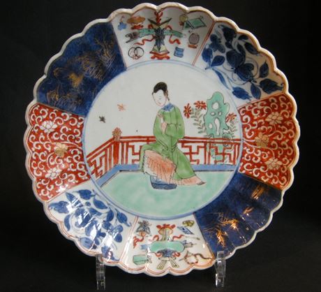 Polychrome : assiette creuse torsadée en porcelaine avec des emaux de la famille verte ,du bleu sous couverte et sur couverte et bleu poudré - Decorée en son centre d une femme de cour  et de decors mobiliers et floral dans des reserves - Chine Epoque Kangxi 1662/1722
