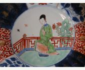 Polychrome : assiette creuse torsadée en porcelaine avec des emaux de la famille verte ,du bleu sous couverte et sur couverte et bleu poudré - Decorée en son centre d une femme de cour  et de decors mobiliers et floral dans des reserves - Chine Epoque Kangxi 1662/1722
