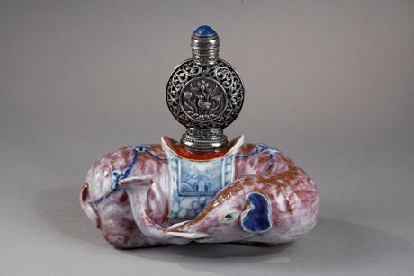 Polychrome : Elephant figure lying in porcelain carrying on its back a silver snuffbottle reticulated in the spirit of Mongolia most probably from the Beijing Imperials workshops and specially adapted for the back of the elephant-
Circa 1790/1820