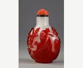 Snuff Bottles : Snuff bottle  red overlay glass with Shou Lao holding a peche of longevity and looking at peches and on the other side of a character holding a cup on a tray in front of a pine - China 1800/1850