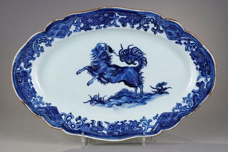 Bleu-Blanc : Petit plat à bord contournés en porcelaine bleu blanc portant un décor d un chien  probablement un epagneul
dressé sur ses pattes arrières sur un sol ou pousse des champignons Lingzi  - Chine epoque Qianlong 1736/1795  