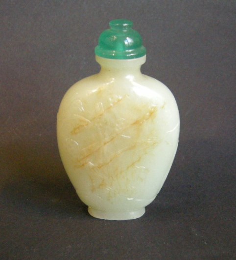 Snuff Bottles : Jade snuff bottle sculpted in a face with birds and prunus  and other face with for caracters  "can you be first laureat" 
1750/1850