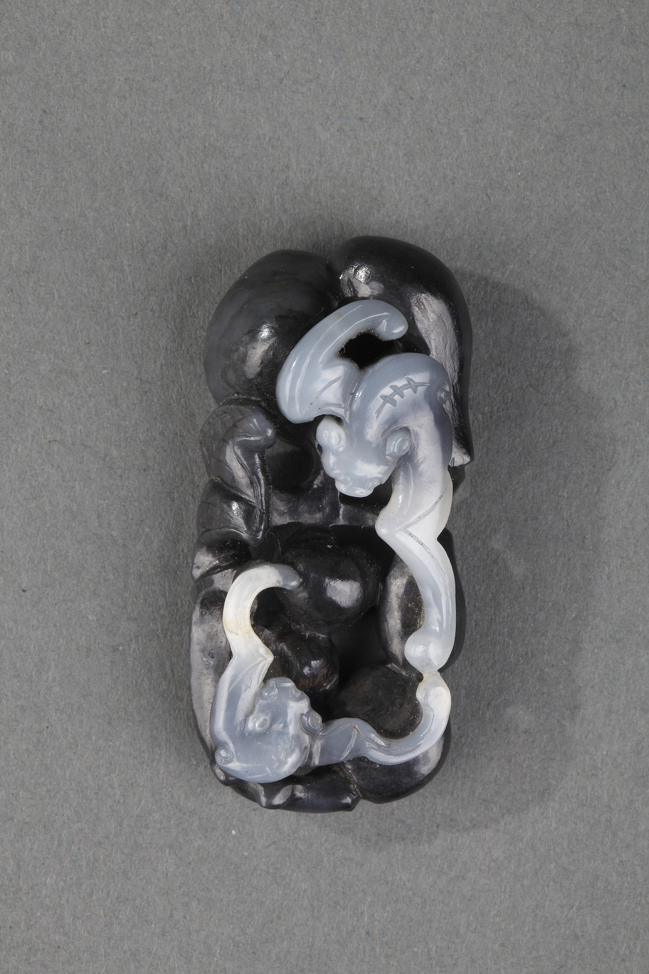 Works of Art : Pendant nephite black and white carved in the shape of two bats with double gourds and their foliage 
Circa 1900