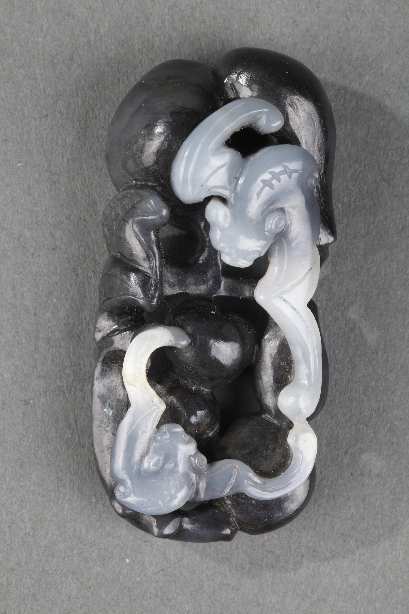 Works of Art : Pendant nephite black and white carved in the shape of two bats with double gourds and their foliage 
Circa 1900