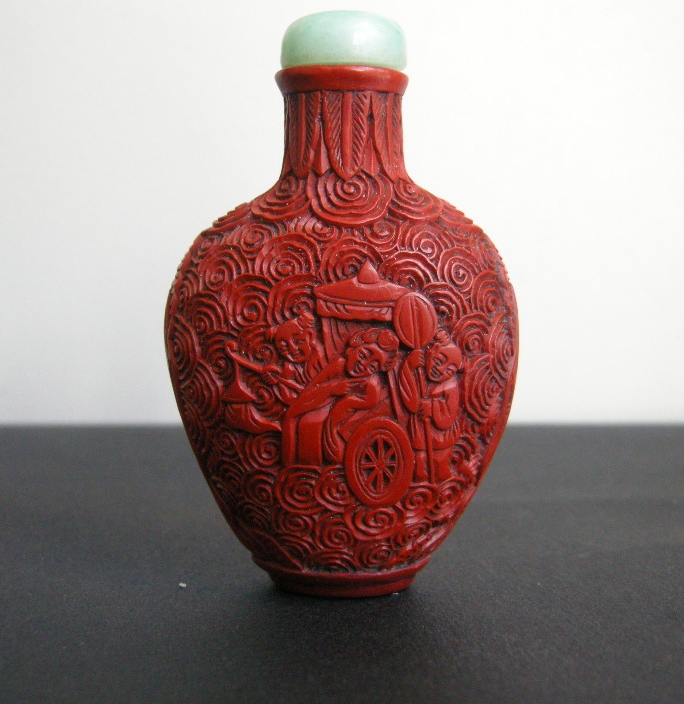 Snuff Bottles : cinnabar lacque snuff bottle on metal decorated and sculpted with a rider on one side and characters on a trolley on the other 
China 19th century
H 6,8 cm