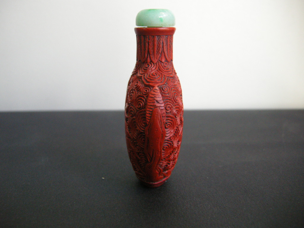 Snuff Bottles : cinnabar lacque snuff bottle on metal decorated and sculpted with a rider on one side and characters on a trolley on the other 
China 19th century
H 6,8 cm