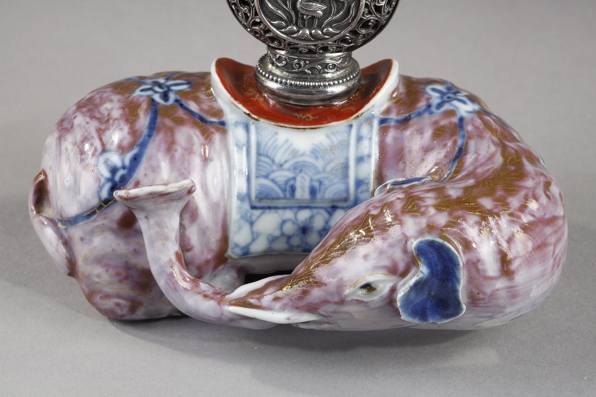 Snuff Bottles : Elephant figure lying in porcelain carrying on its back a silver snuffbottle reticulated in the spirit of Mongolia most probably from the Beijing Imperials workshops and specially adapted for the back of the elephant-
Circa 1790/1820