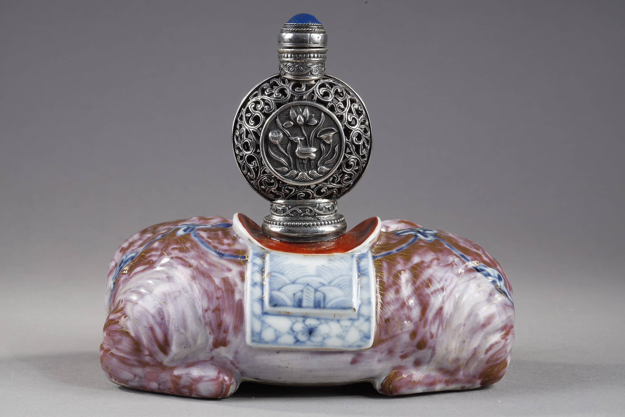 Snuff Bottles : Elephant figure lying in porcelain carrying on its back a silver snuffbottle reticulated in the spirit of Mongolia most probably from the Beijing Imperials workshops and specially adapted for the back of the elephant-
Circa 1790/1820