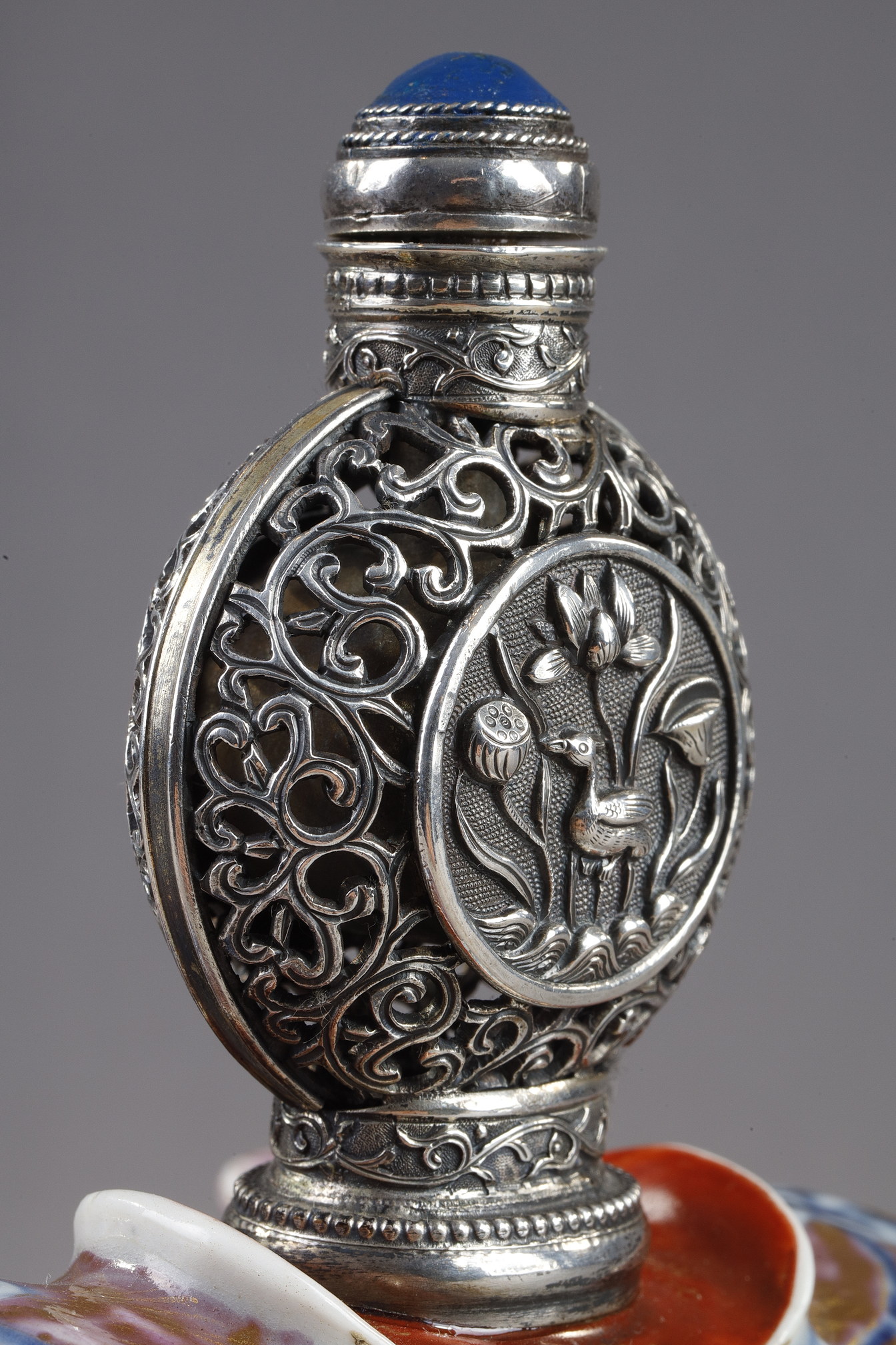 Snuff Bottles : Elephant figure lying in porcelain carrying on its back a silver snuffbottle reticulated in the spirit of Mongolia most probably from the Beijing Imperials workshops and specially adapted for the back of the elephant-
Circa 1790/1820