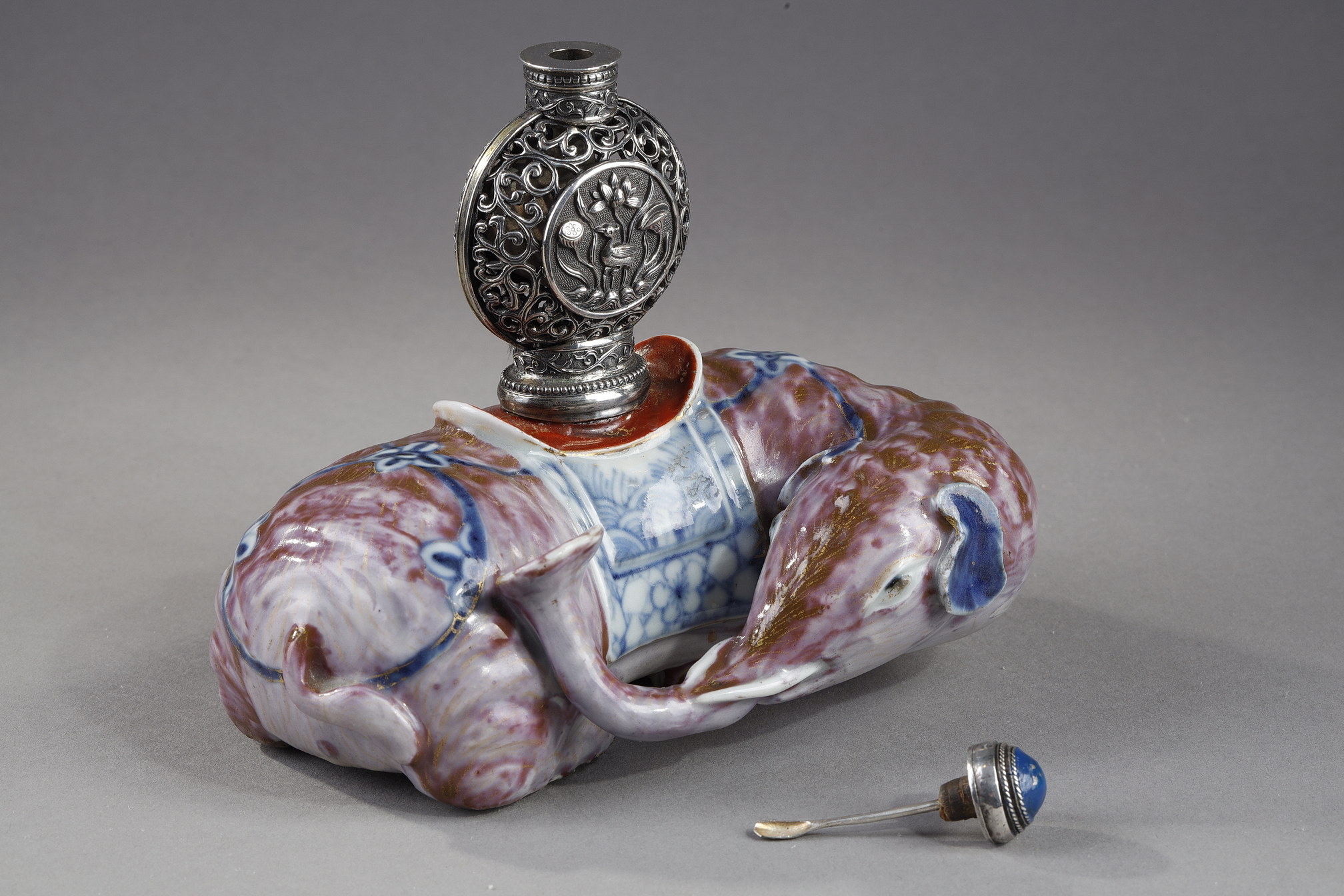 Snuff Bottles : Elephant figure lying in porcelain carrying on its back a silver snuffbottle reticulated in the spirit of Mongolia most probably from the Beijing Imperials workshops and specially adapted for the back of the elephant-
Circa 1790/1820