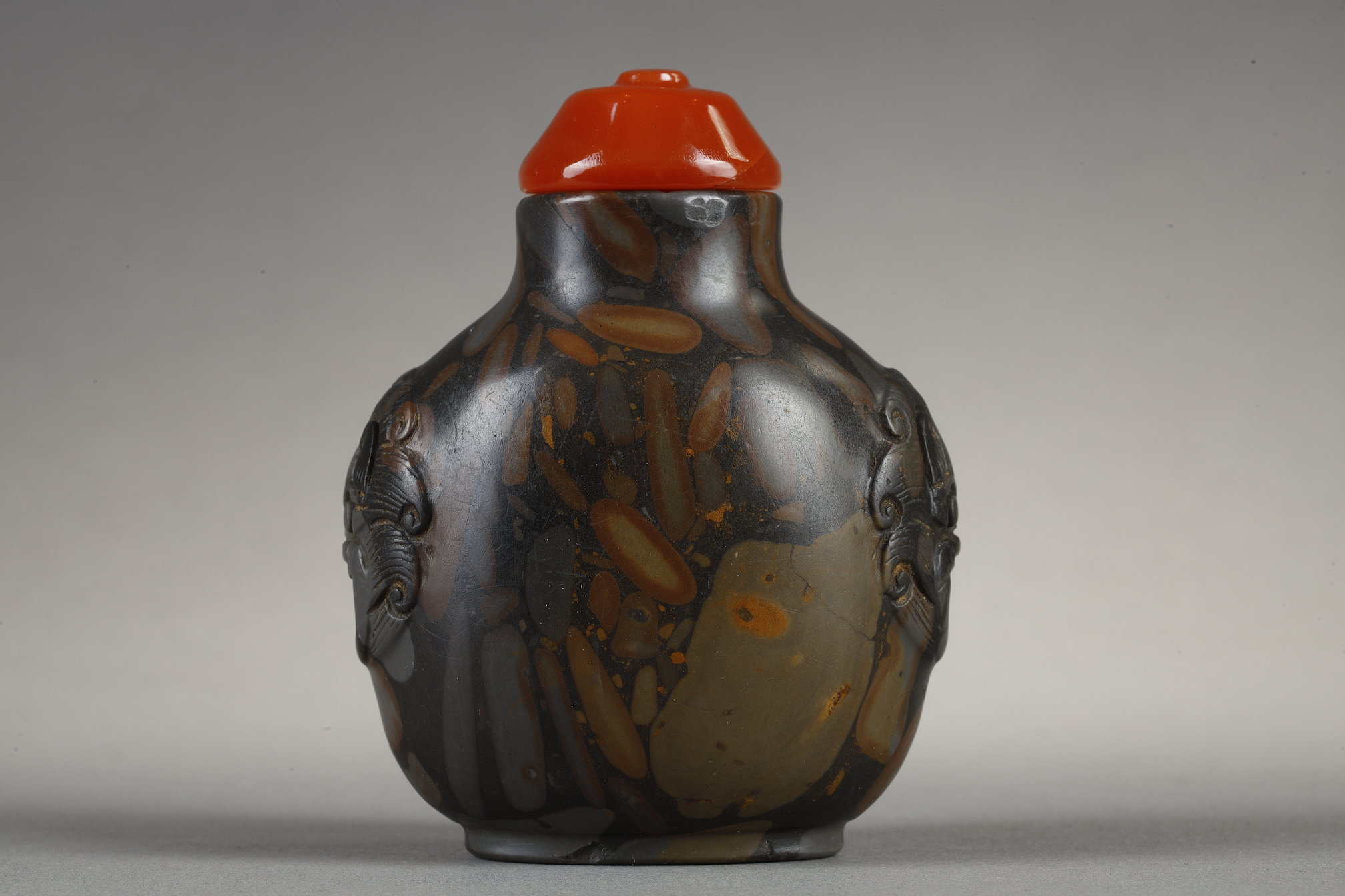 Snuff Bottles : Snuff bottle in puddingstone  sculpté de masques sur les cotés
Chine 19th century 