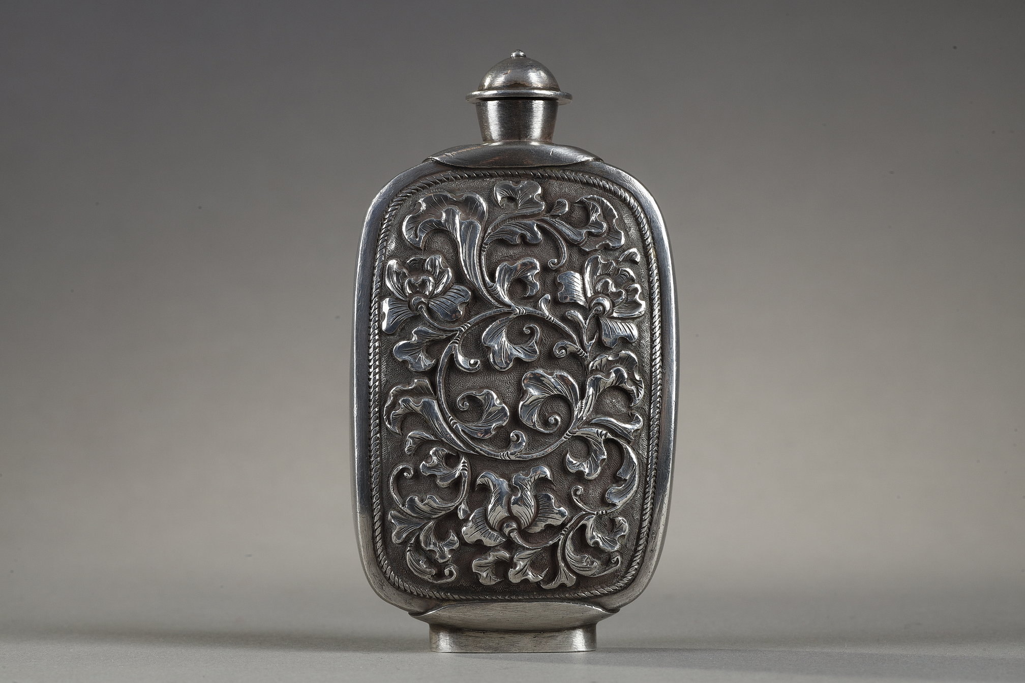 Snuff Bottles : Snuff bottle in the form of a speckled rusty jade pebble (1750/1850) included in a silver frame 
ciseled from the stem of leaves (late Qing period) -