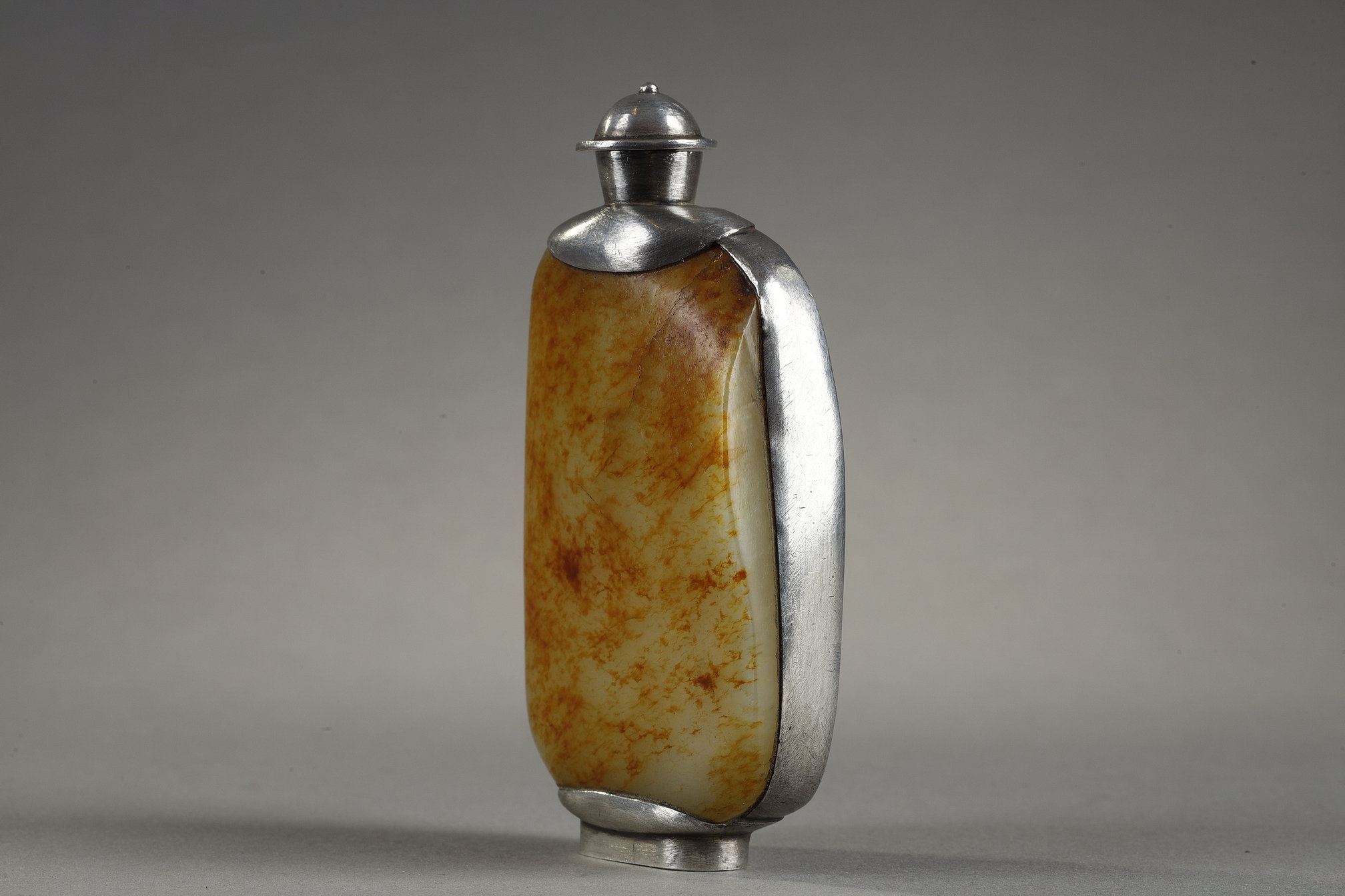 Snuff Bottles : Snuff bottle in the form of a speckled rusty jade pebble (1750/1850) included in a silver frame 
ciseled from the stem of leaves (late Qing period) -