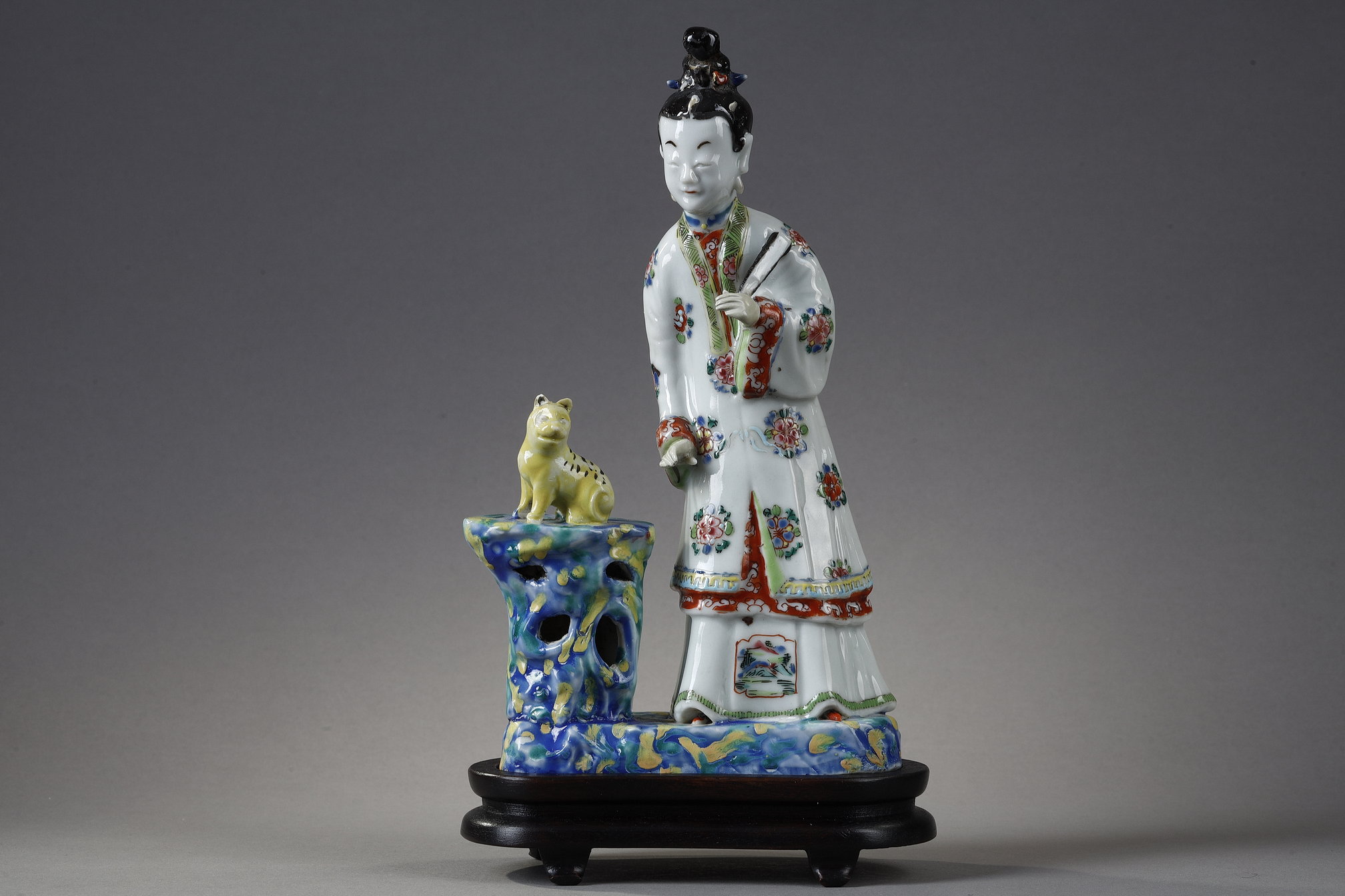 Polychrome : Porcelain group depicting a court woman standing and holding a fan next to a cat sitting on a rock. China around 1730 -   
H 22cm
