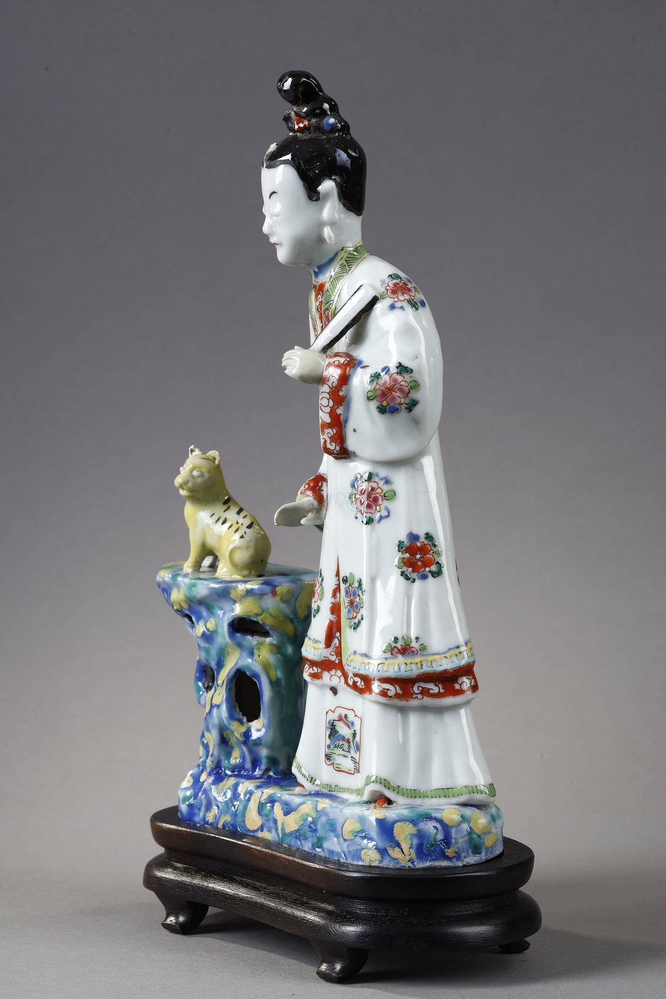 Polychrome : Porcelain group depicting a court woman standing and holding a fan next to a cat sitting on a rock. China around 1730 -   
H 22cm
