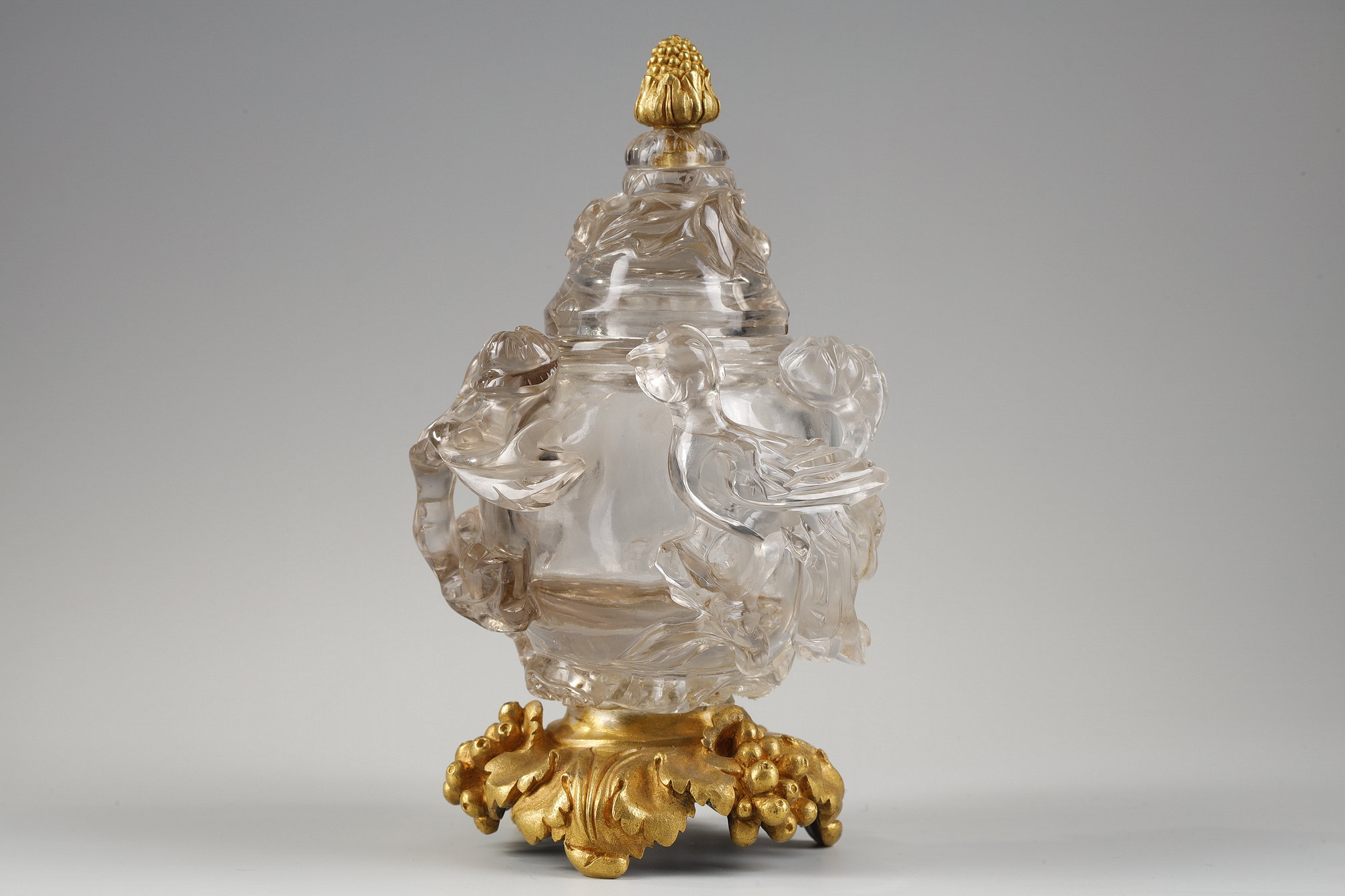 Works of Art : Carved rock crystal covered vase in the shape of a jug with a spout shaped like a bird’s head
China 19em siécle Posterior bronze mount adorned with bunches of grapes.   H 17cm