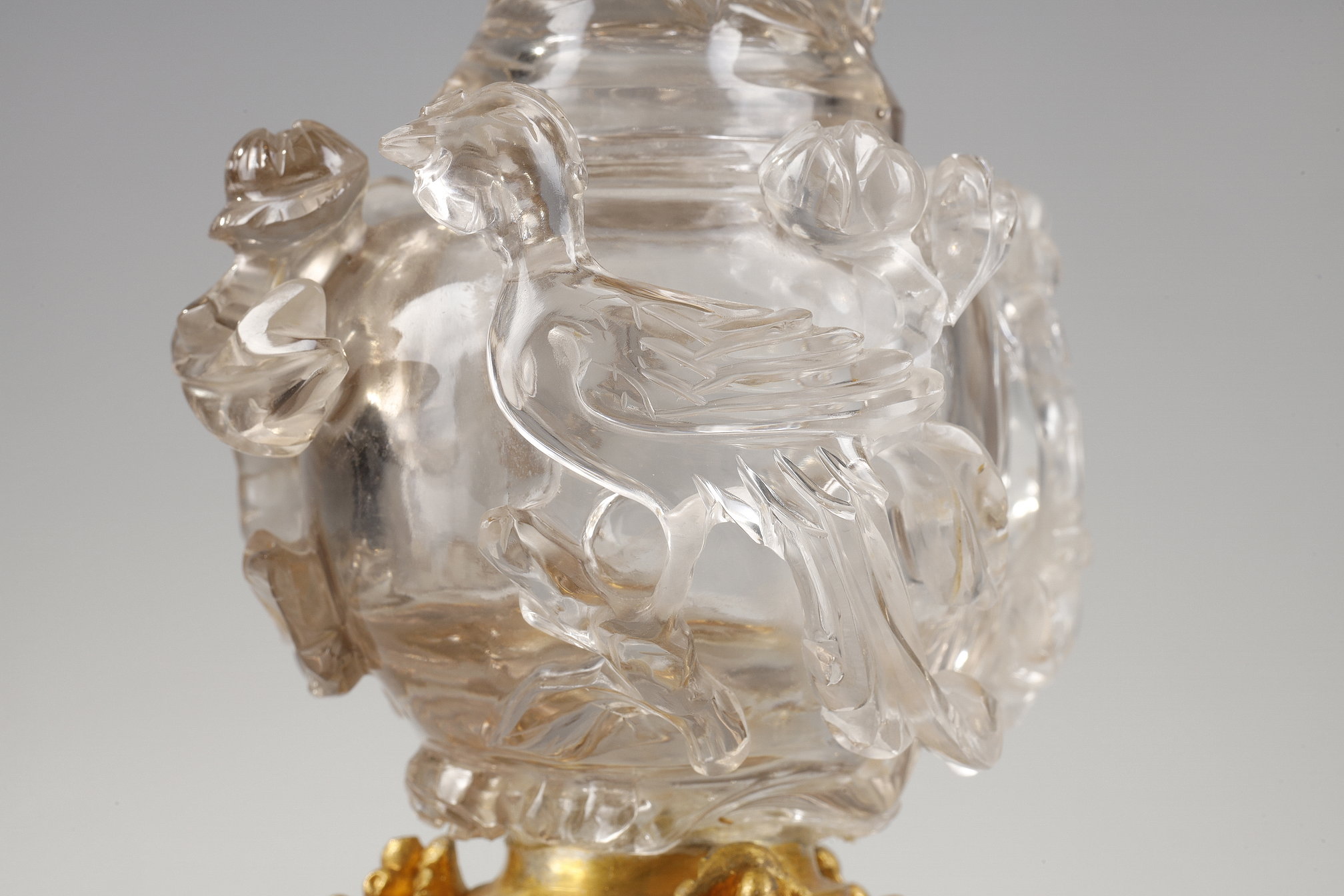 Works of Art : Carved rock crystal covered vase in the shape of a jug with a spout shaped like a bird’s head
China 19em siécle Posterior bronze mount adorned with bunches of grapes.   H 17cm