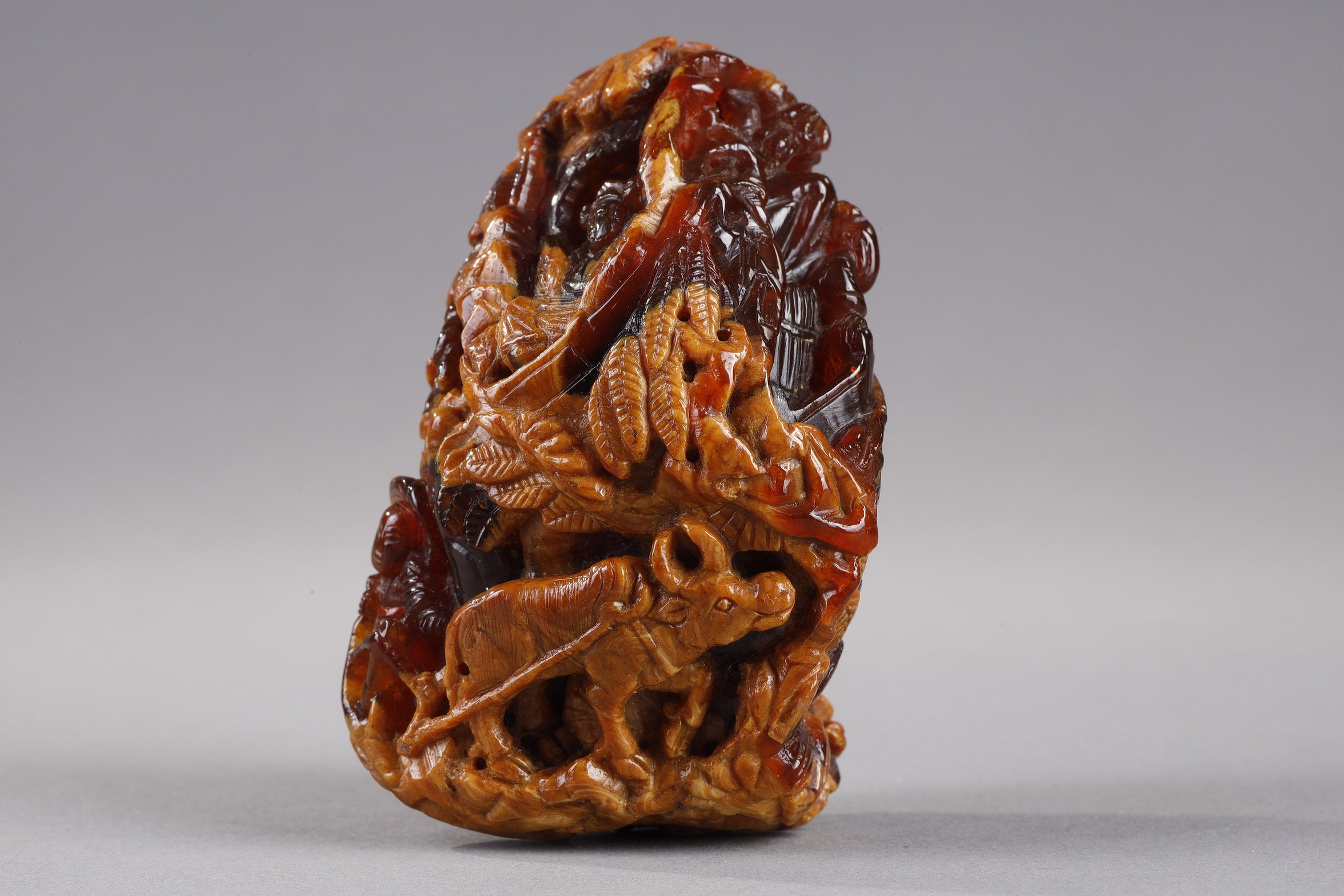 Works of Art : Pendant in amber root finely carved with a buffalo and several characters in a landscape - China 19th century