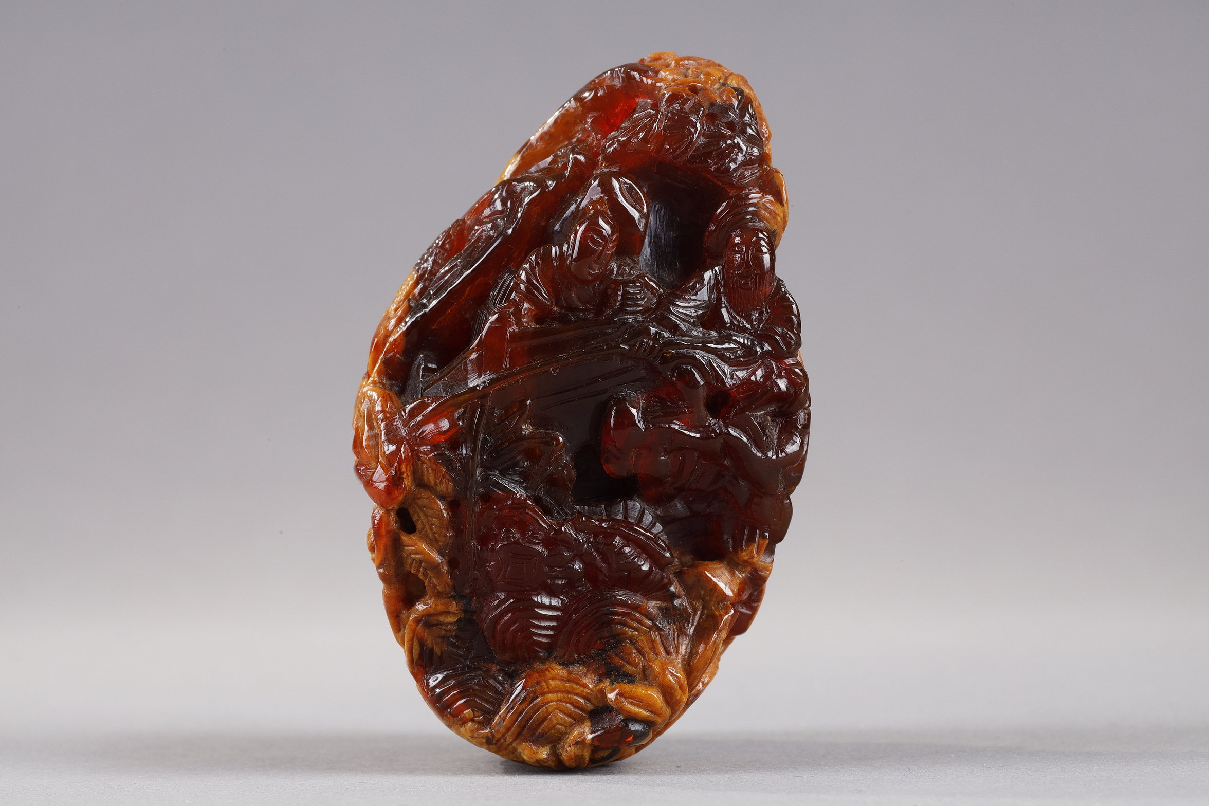 Works of Art : Pendant in amber root finely carved with a buffalo and several characters in a landscape - China 19th century