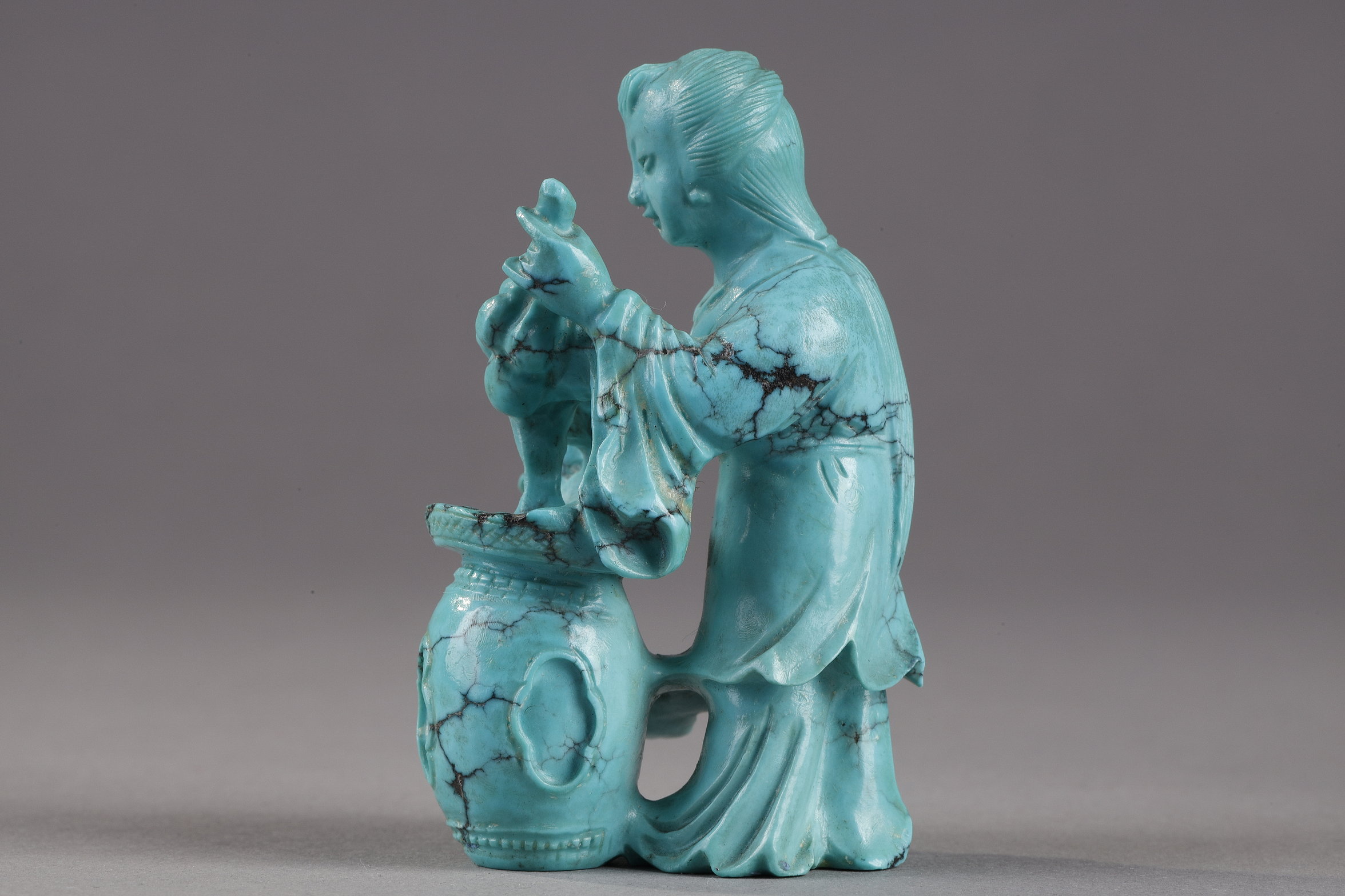 Works of Art : Finely carved turquoise statuettes - China Qing period circa 1900
1)Depicting a young woman pressing fruit on a tray on a barrel-shaped stool 
2) representing a child on a soapstone base 