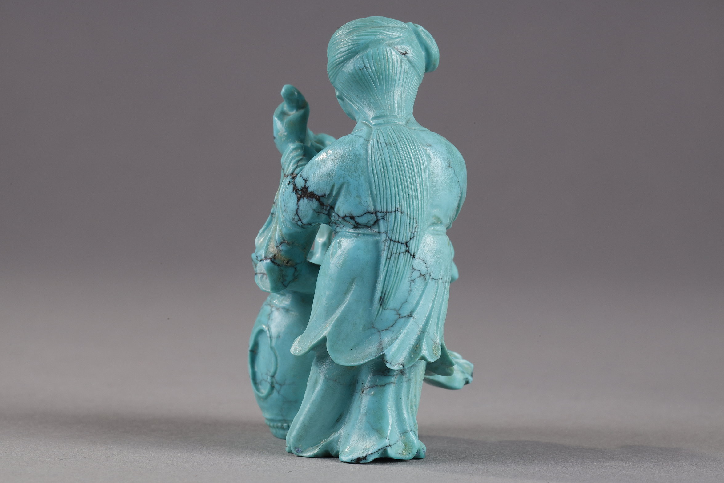Works of Art : Finely carved turquoise statuettes - China Qing period circa 1900
1)Depicting a young woman pressing fruit on a tray on a barrel-shaped stool 
2) representing a child on a soapstone base 