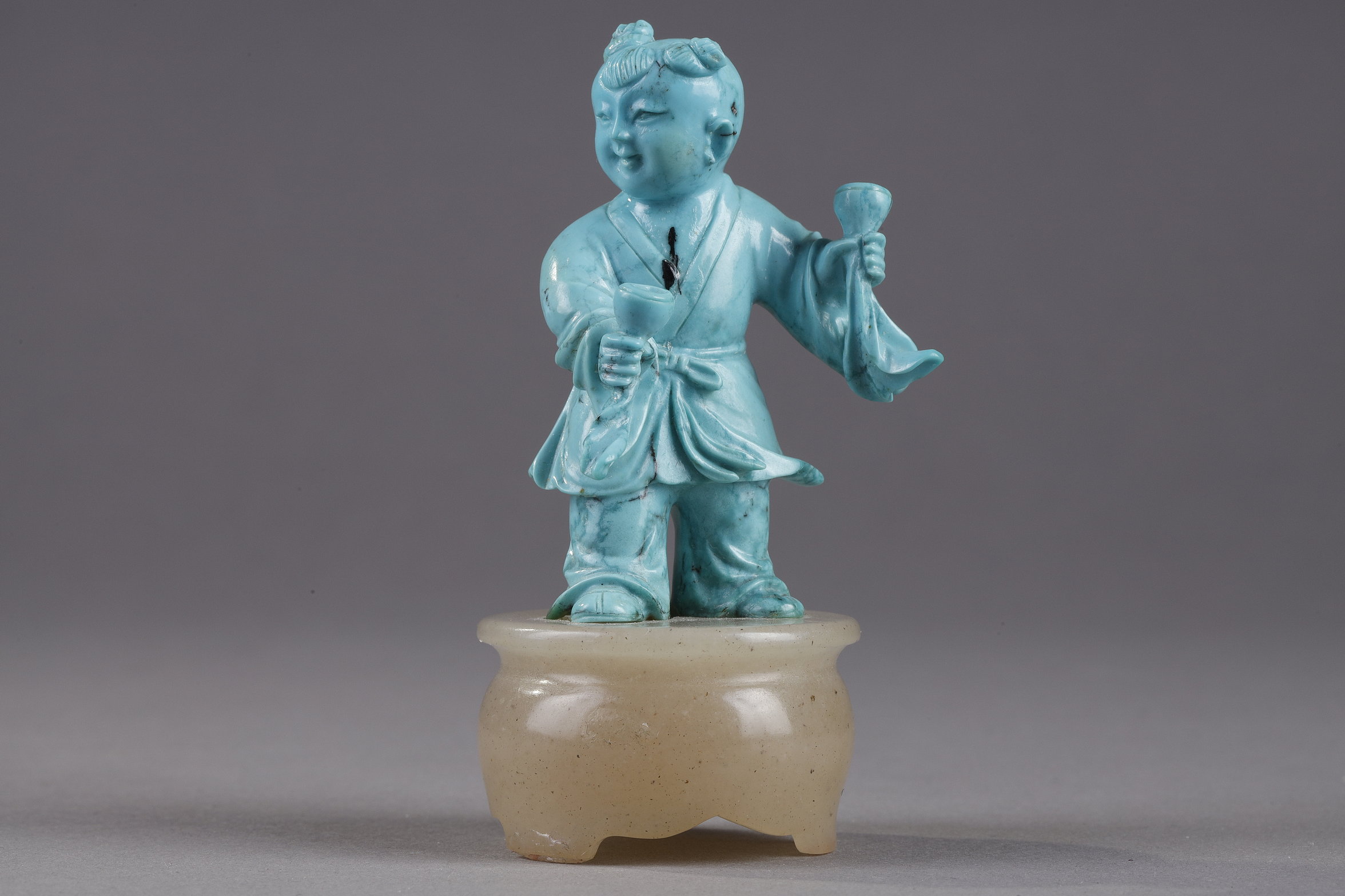 Works of Art : Finely carved turquoise statuettes - China Qing period circa 1900
1)Depicting a young woman pressing fruit on a tray on a barrel-shaped stool 
2) representing a child on a soapstone base 