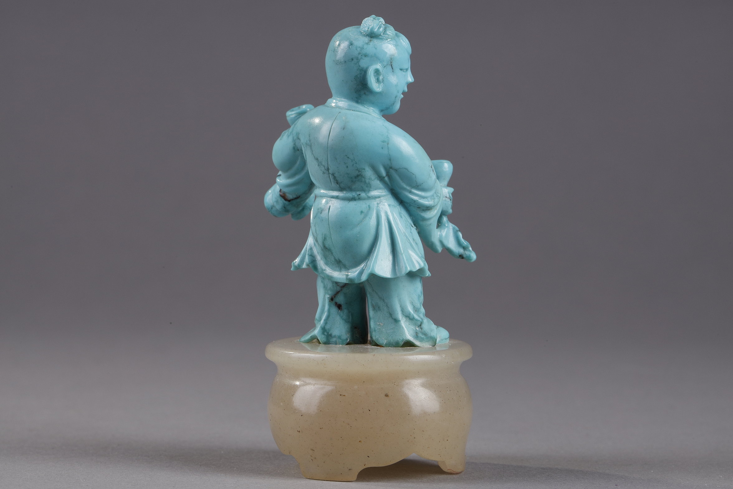 Works of Art : Finely carved turquoise statuettes - China Qing period circa 1900
1)Depicting a young woman pressing fruit on a tray on a barrel-shaped stool 
2) representing a child on a soapstone base 
