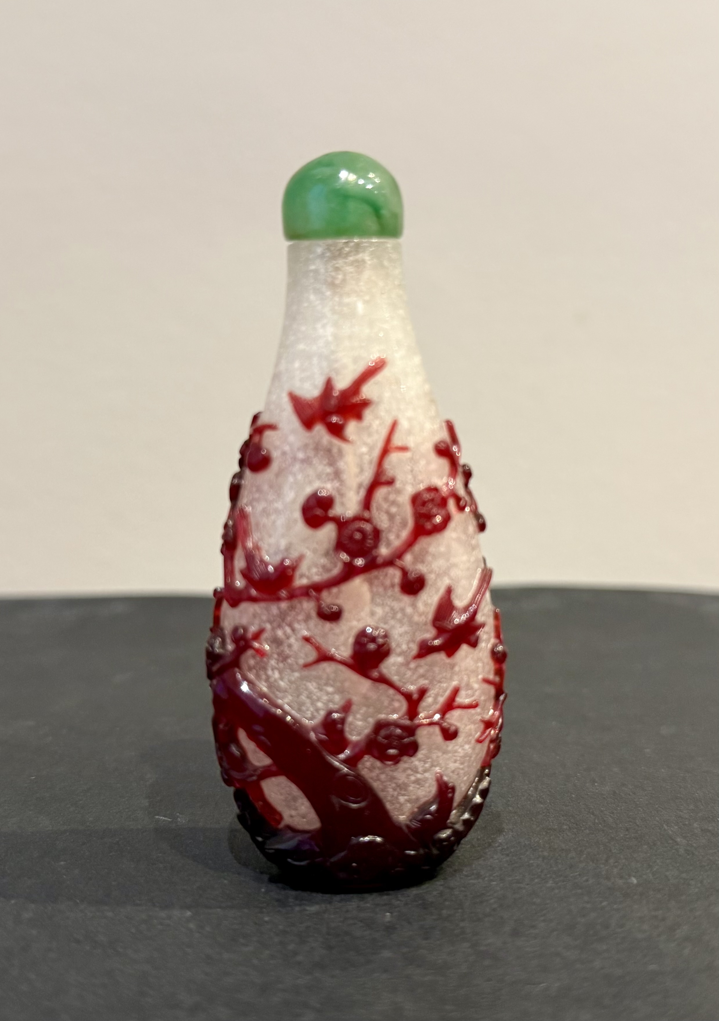 Tabatières : Tabatière en verre "overlay rouge" rubis finement sculpté sur fond bullé translucide à décor des douze pies en vol et perchées sur un tronc de prunus en fleurs et rocher  Chine 1750/80 