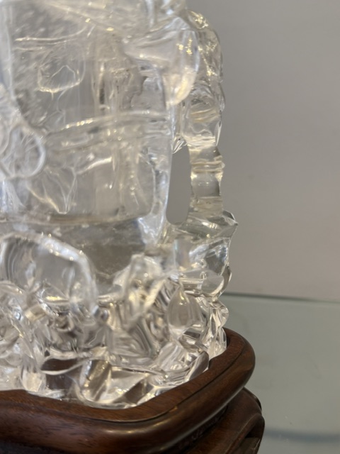 Works of Art : Rock crystal vase of bamboo double trunk form ,the sides carved in relief with pines and a bird perched on the branch facing a deer ,and a tree with grenades adorned with a phenix standing on a rock base facing a qilong at the top of the vase 
China 19th century    H 19cm
with wood stand
