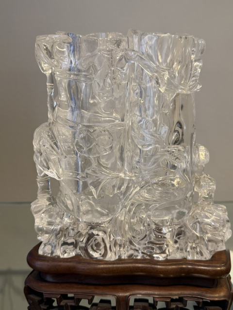 Works of Art : Rock crystal vase of bamboo double trunk form ,the sides carved in relief with pines and a bird perched on the branch facing a deer ,and a tree with grenades adorned with a phenix standing on a rock base facing a qilong at the top of the vase 
China 19th century    H 19cm
with wood stand
